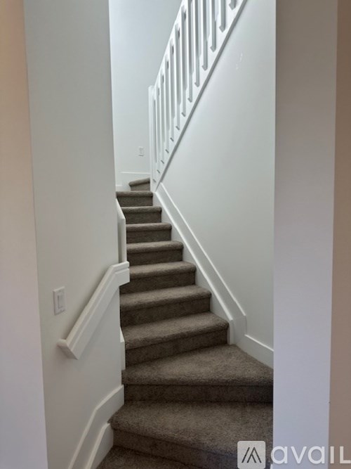 A staircase with a beige carpet and white railings.