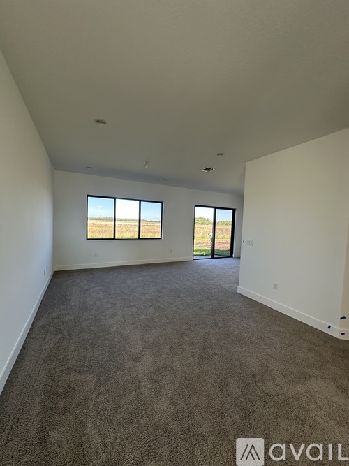A spacious room with carpeted floor and large windows.