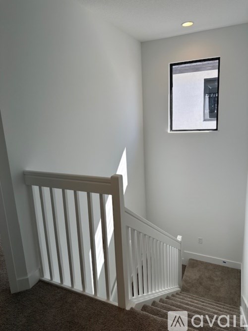 A white staircase with a carpeted stairway and a picture frame on the wall.