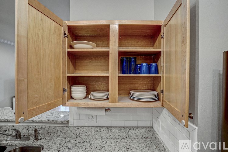 A kitchen cabinet with plates and cups inside.