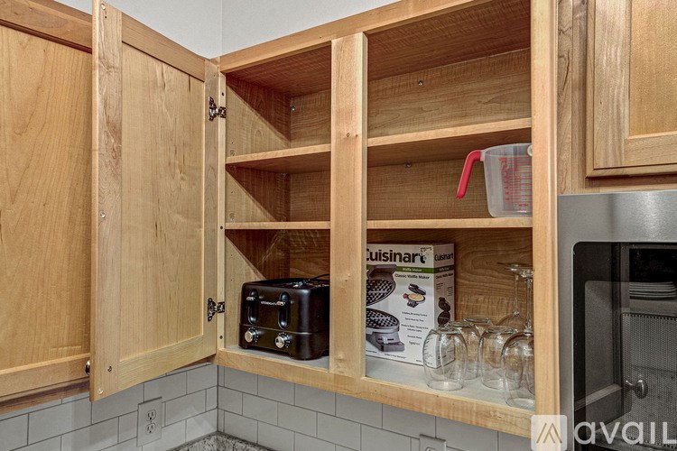 A kitchen cabinet with a toaster and measuring cups inside.
