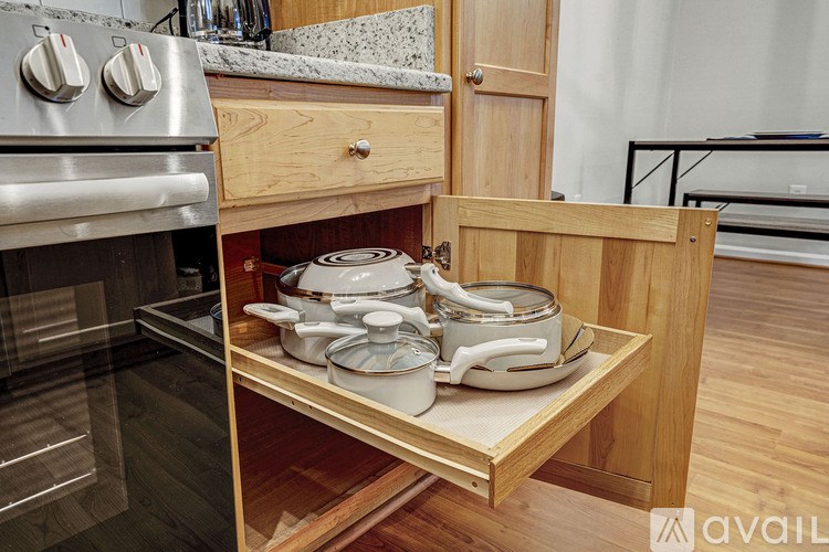 A kitchen with a stove and a drawer with pots and pans.
