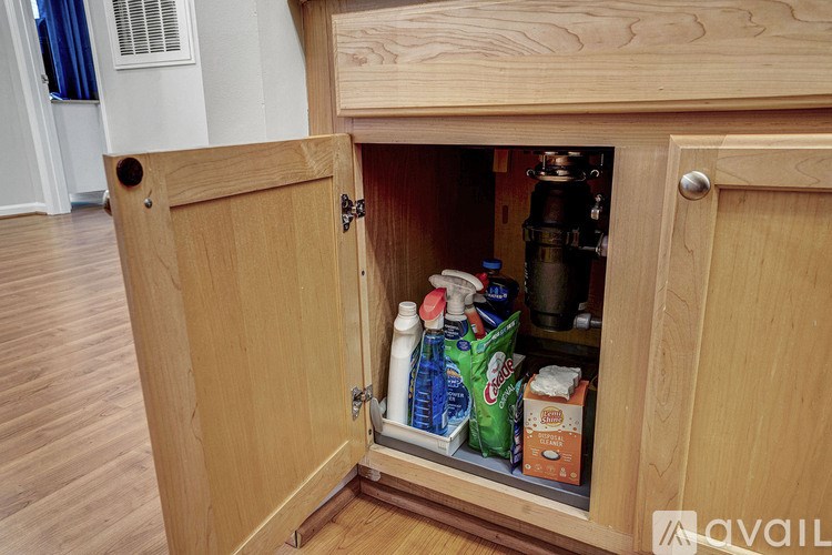 A wooden cabinet with a door open revealing a variety of items inside.