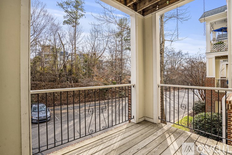 A balcony with a black railing and a car parked on the street.