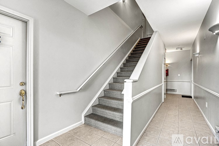 A hallway with a staircase and a white door.
