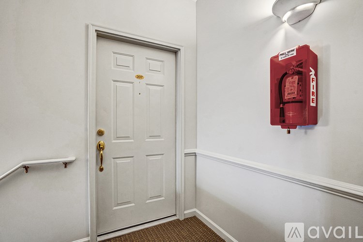 A white door with a red fire extinguisher on the wall.
