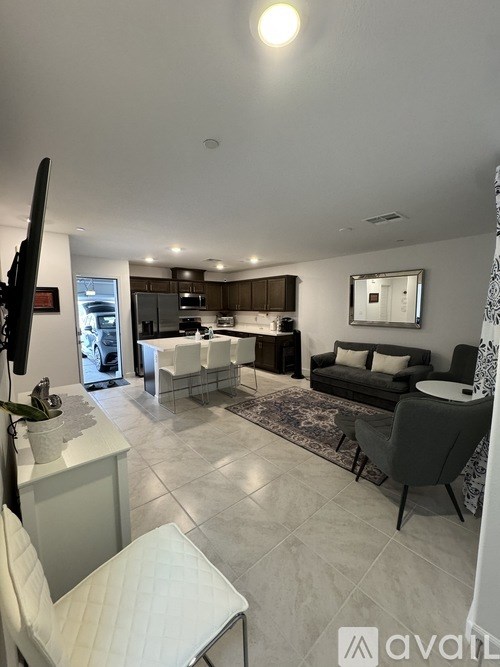A modern living room with a kitchen area in the background.