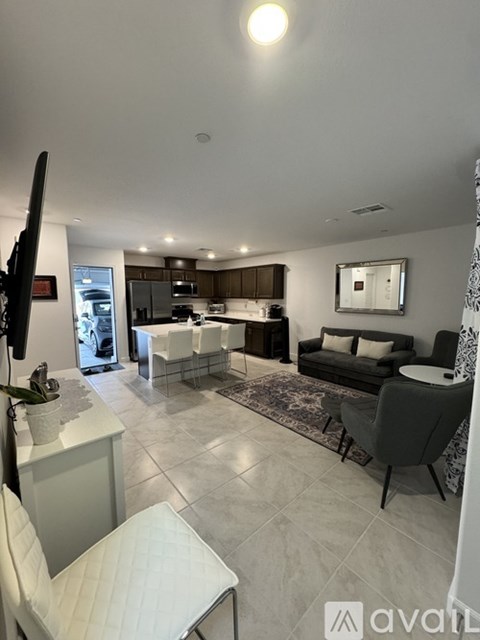 A modern living room with a kitchen area in the background.