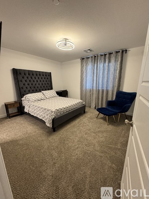 A bedroom with a large bed and a blue chair.