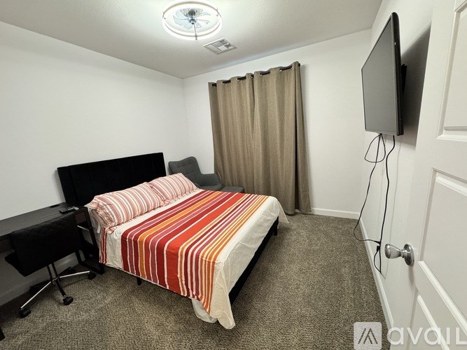 A bedroom with a bed, desk, and television.