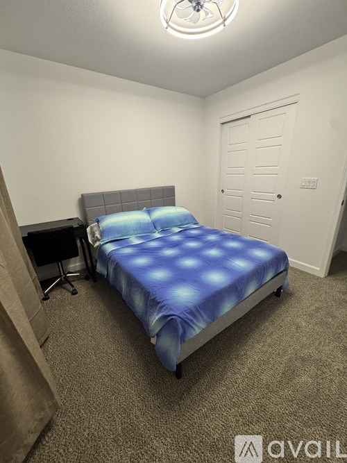A bedroom with a bed, desk, and chair.