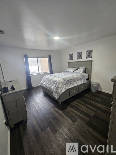 A bedroom with a bed, nightstand, and window.
