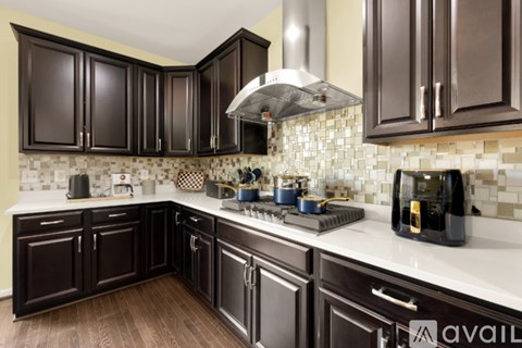 A kitchen with dark brown cabinets and a white countertop.