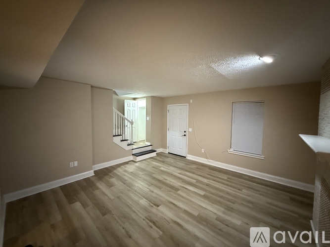 A room with wooden flooring and a staircase leading to another room.