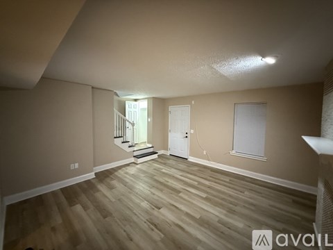 A room with wooden flooring and a staircase leading to another room.