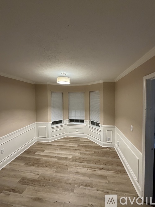 A room with a light on the ceiling and a window with blinds.