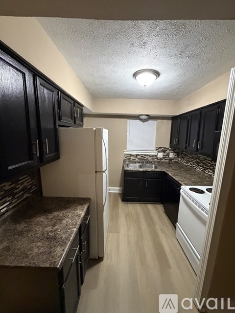 A kitchen with black cabinets and a refrigerator.