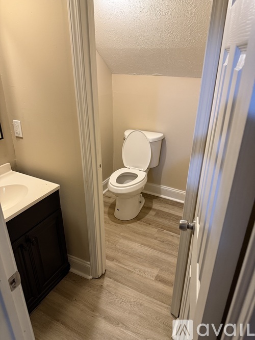 A bathroom with a toilet, sink, and cabinet.