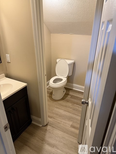 A bathroom with a toilet, sink, and cabinet.