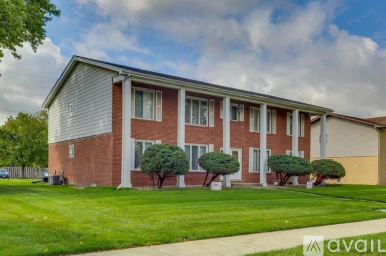 A brick apartment building with a green lawn in front.