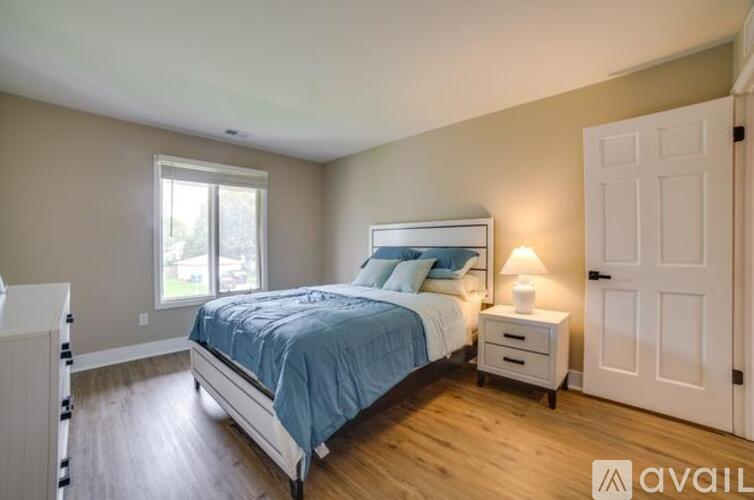 A bedroom with a bed, nightstand, and window.
