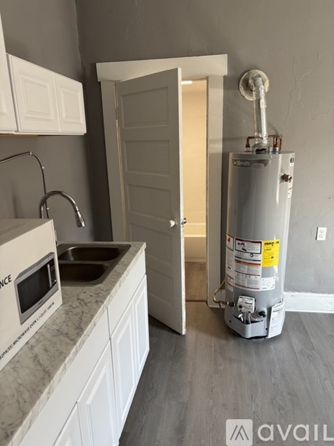 A kitchen with a water heater in the corner.