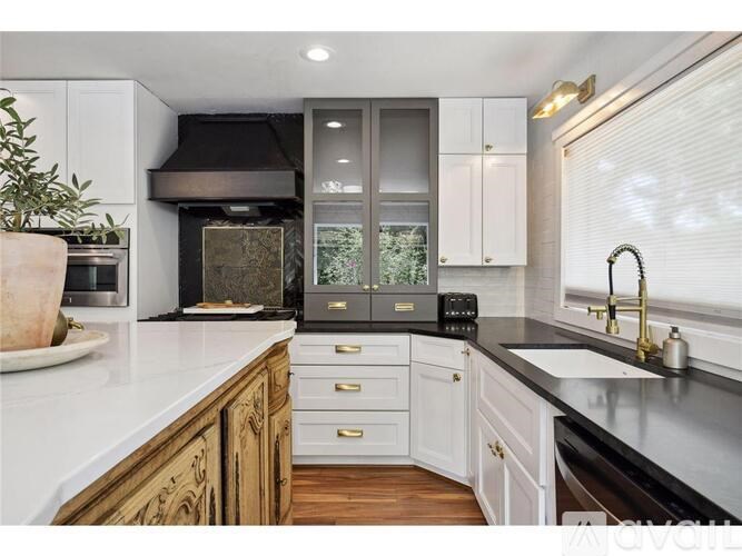 A kitchen with white cabinets and a black countertop.