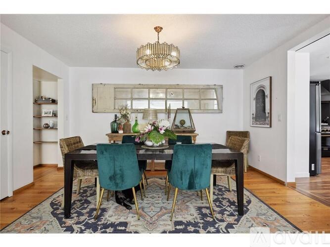 A dining room with a table set for two and a chandelier hanging from the ceiling.