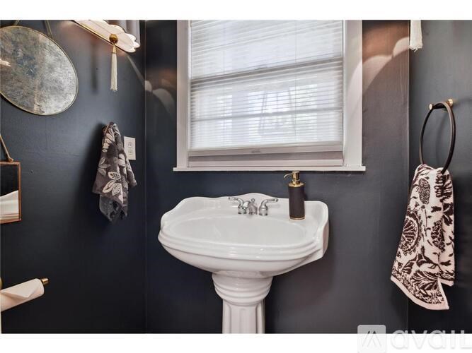 A white pedestal sink with a silver faucet is in a bathroom with a window.