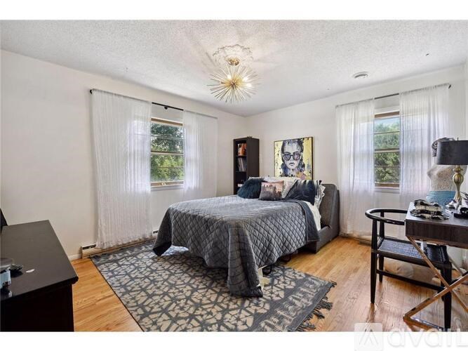 A bedroom with a bed, a chair, and a painting on the wall.