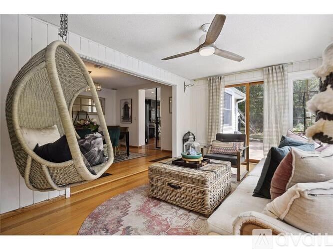 A living room with a hanging egg chair and a wicker coffee table.