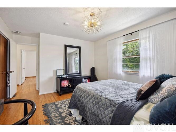 A bedroom with a bed, dresser, mirror, and chair.