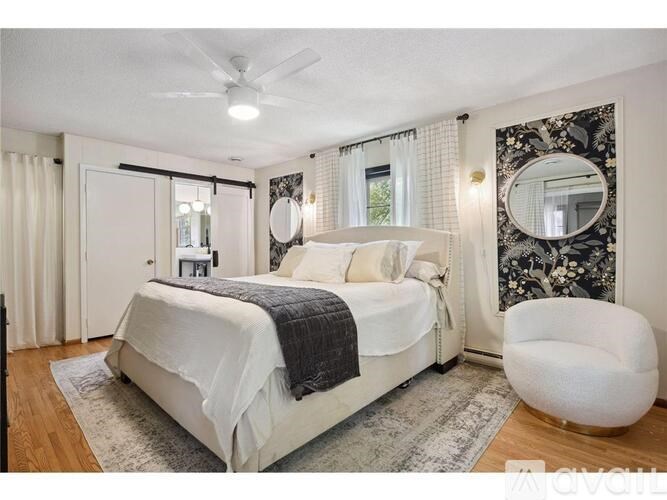 A bedroom with a large bed, a ceiling fan, and a chair.