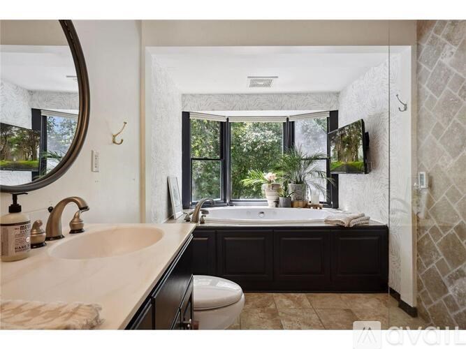 A bathroom with a large mirror, sink, and bathtub.