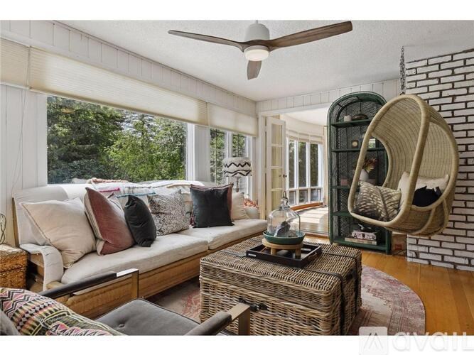 A living room with a white couch, a wicker chair, and a ceiling fan.