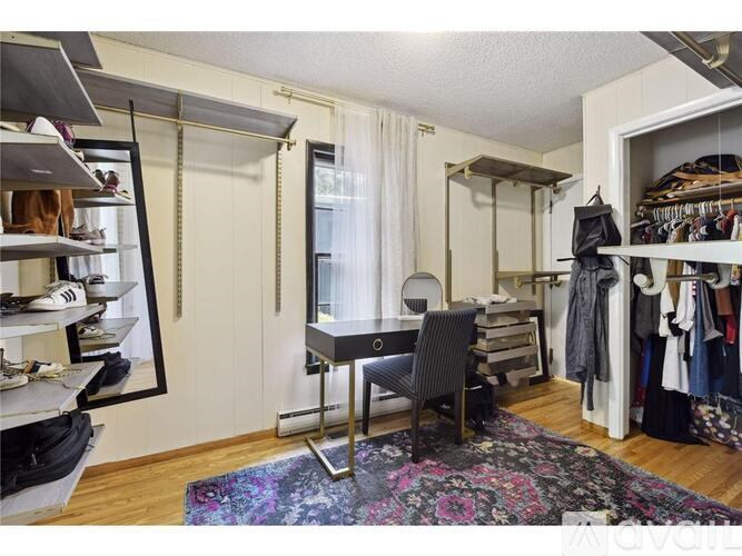 A room with a chair, a mirror, and a clothing rack.