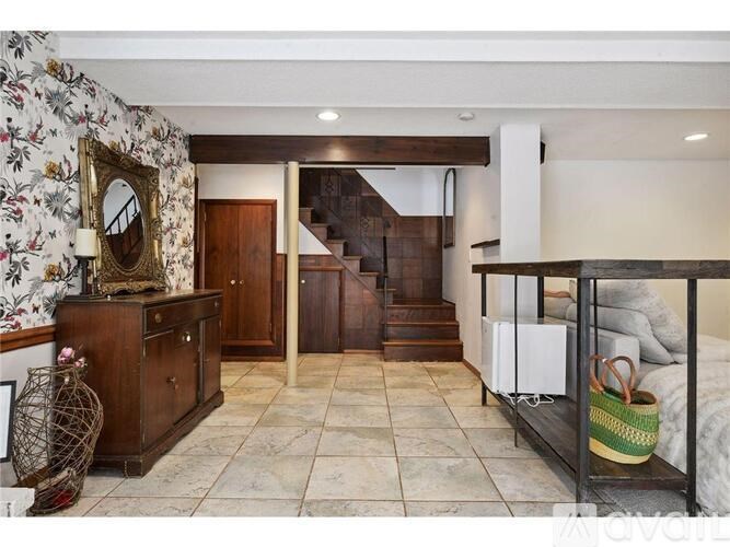A room with a staircase and a mirror on a dresser.