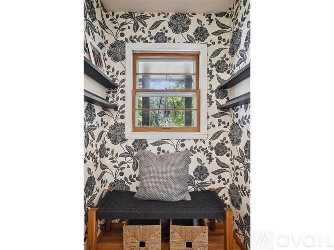 A window with a view of trees and a chair with a pillow on a bench.