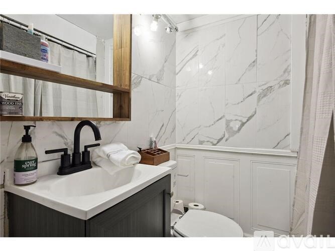 A bathroom with a marble wall and a wooden mirror frame.