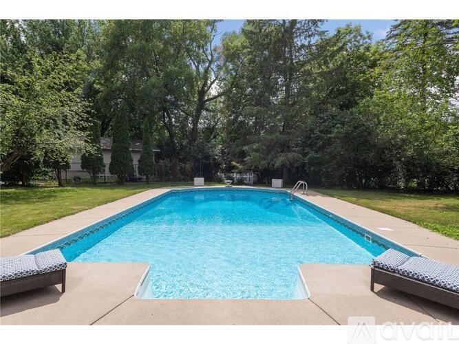 A large blue swimming pool surrounded by trees and a concrete patio.