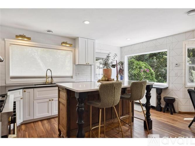 A kitchen with a bar area and a window overlooking a green area.