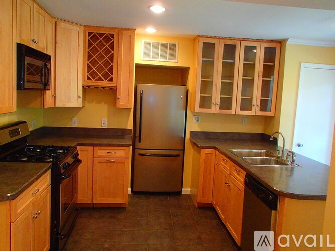 A kitchen with wooden cabinets and a stainless steel refrigerator.
