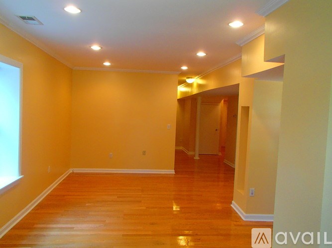A spacious room with wooden floors and a large window.