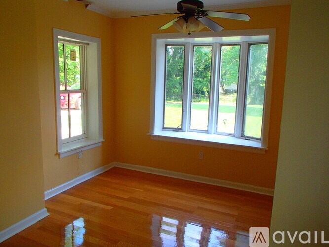 A room with a ceiling fan and a window overlooking a lawn.