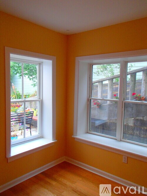 Two windows with white frames and glass panes, one with a view of a patio and the other with a view of a balcony.