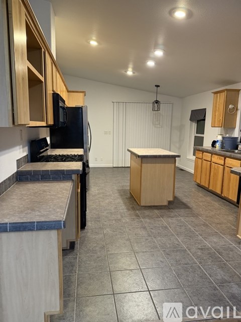 A kitchen with wooden cabinets and a black refrigerator.