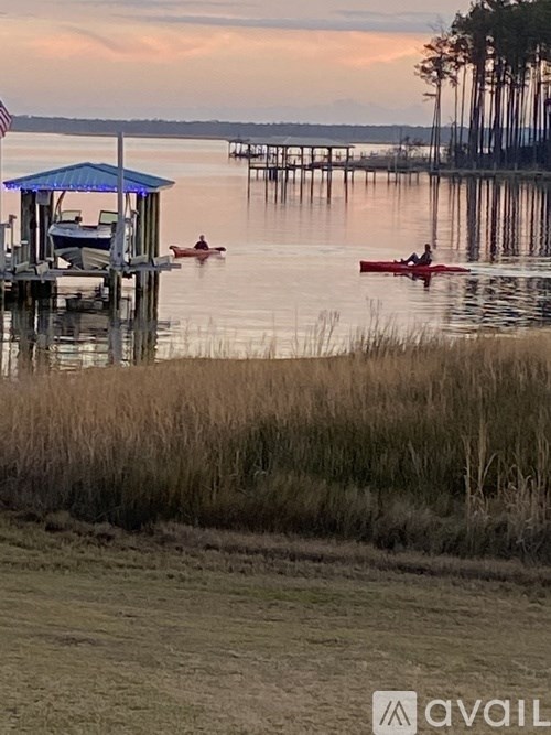 A serene lakeside scene with a dock and two people kayaking.