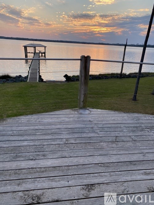 A wooden dock extends into a calm body of water under a twilight sky.