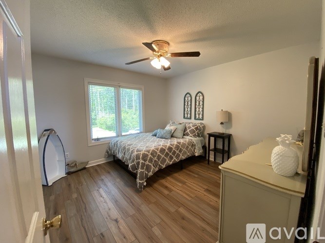 A bedroom with a bed, a window, and a ceiling fan.