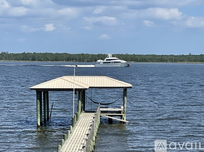 A boat is sailing in the distance behind a wooden pier.